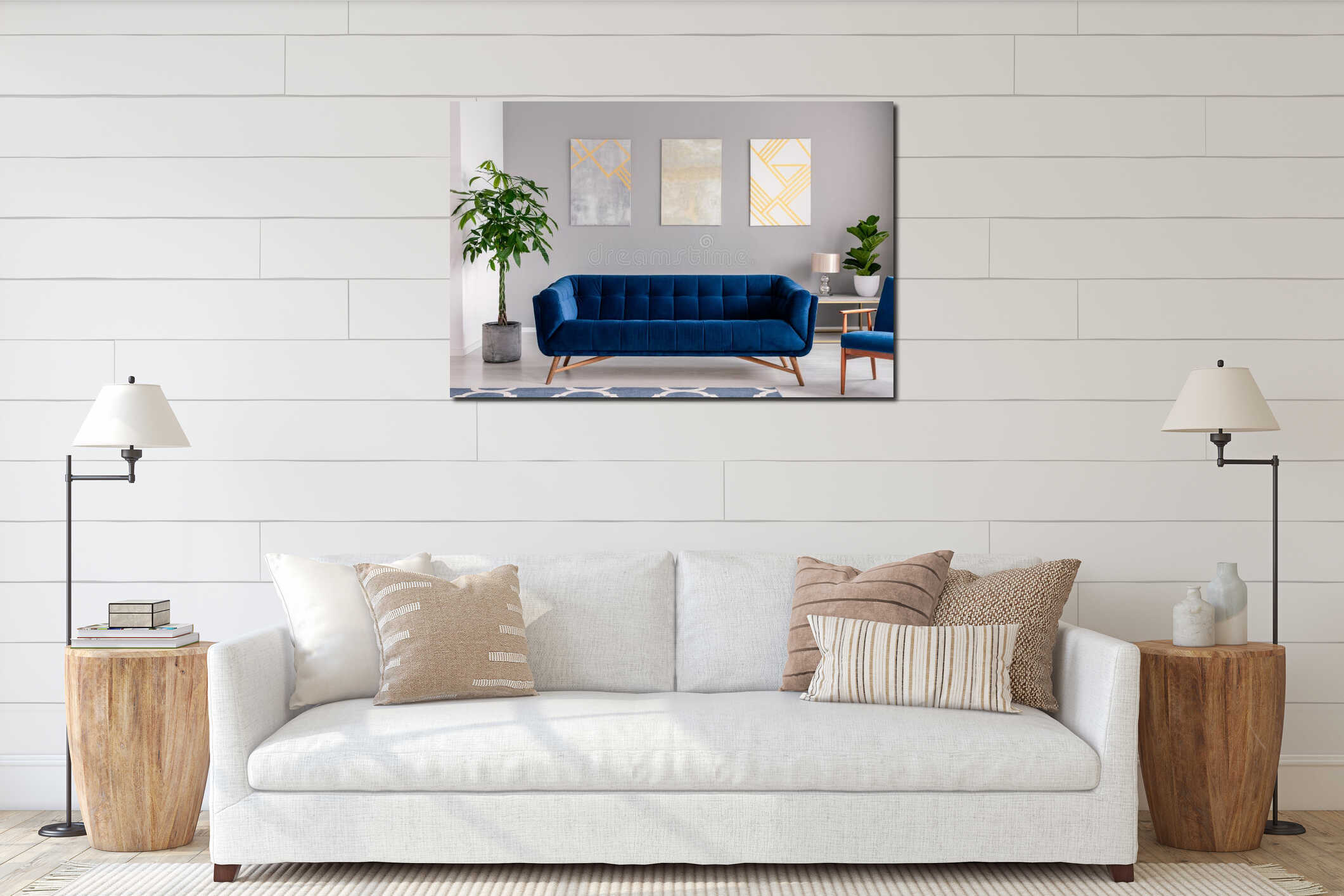A dark blue velvet couch in front of a gray wall with graphic paintings in a modern living room interior. Real photo. interior mockup