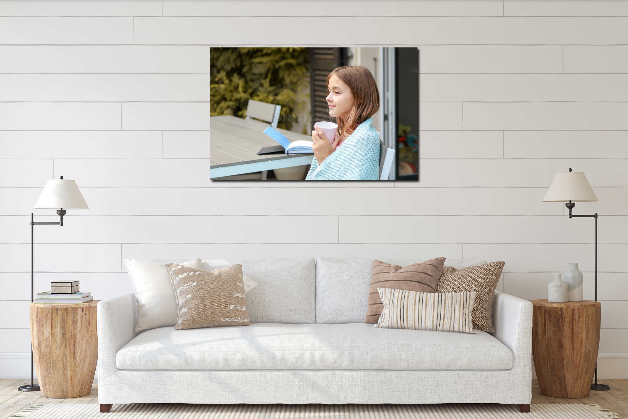 Beautiful smiling young girl daydreaming with cup of tea in her hands and book on table interior mockup
