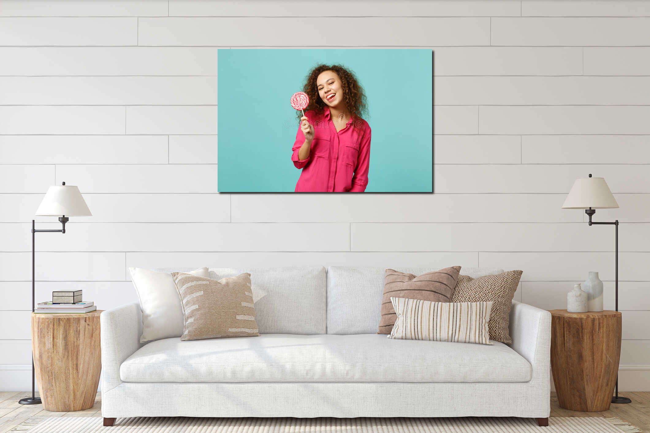 Funny african girl in casual clothes holding in hand pink round lollipop showing tongue  on blue turquoise interior mockup