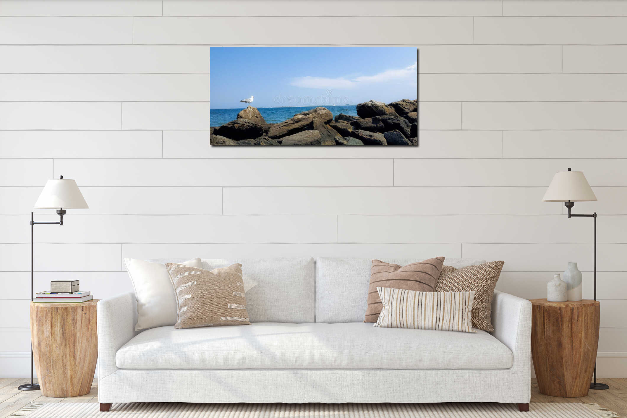 Seagull sitting on rocks by ocean interior mockup