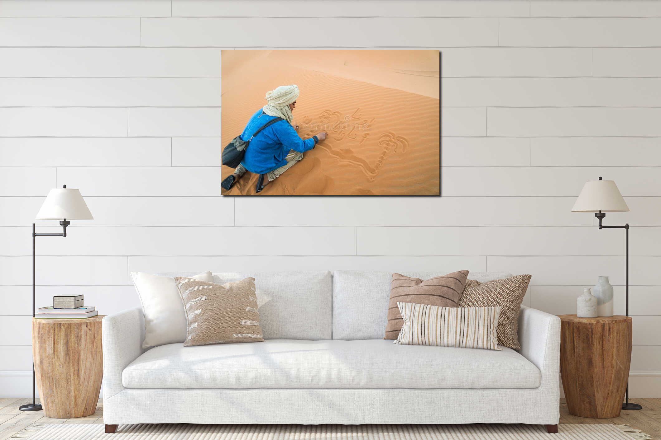 Merzouga, Morocco - APRIL 29 2019: Traditionally dressed Moroccan drawing in the sand of the Sahara Desert interior mockup