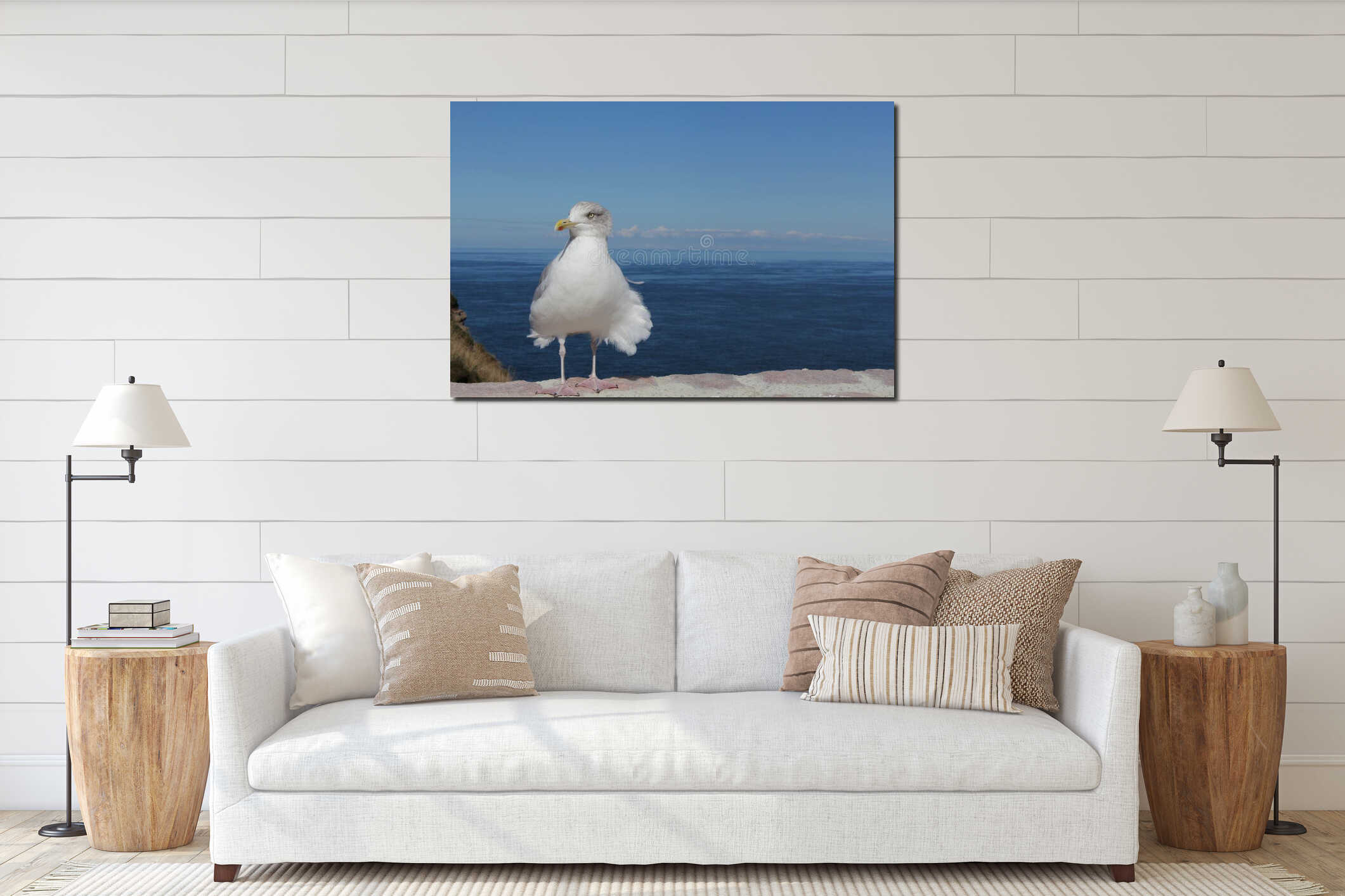 A white seagull sits in the wind in front of a blue sea and sky at the european coast interior mockup