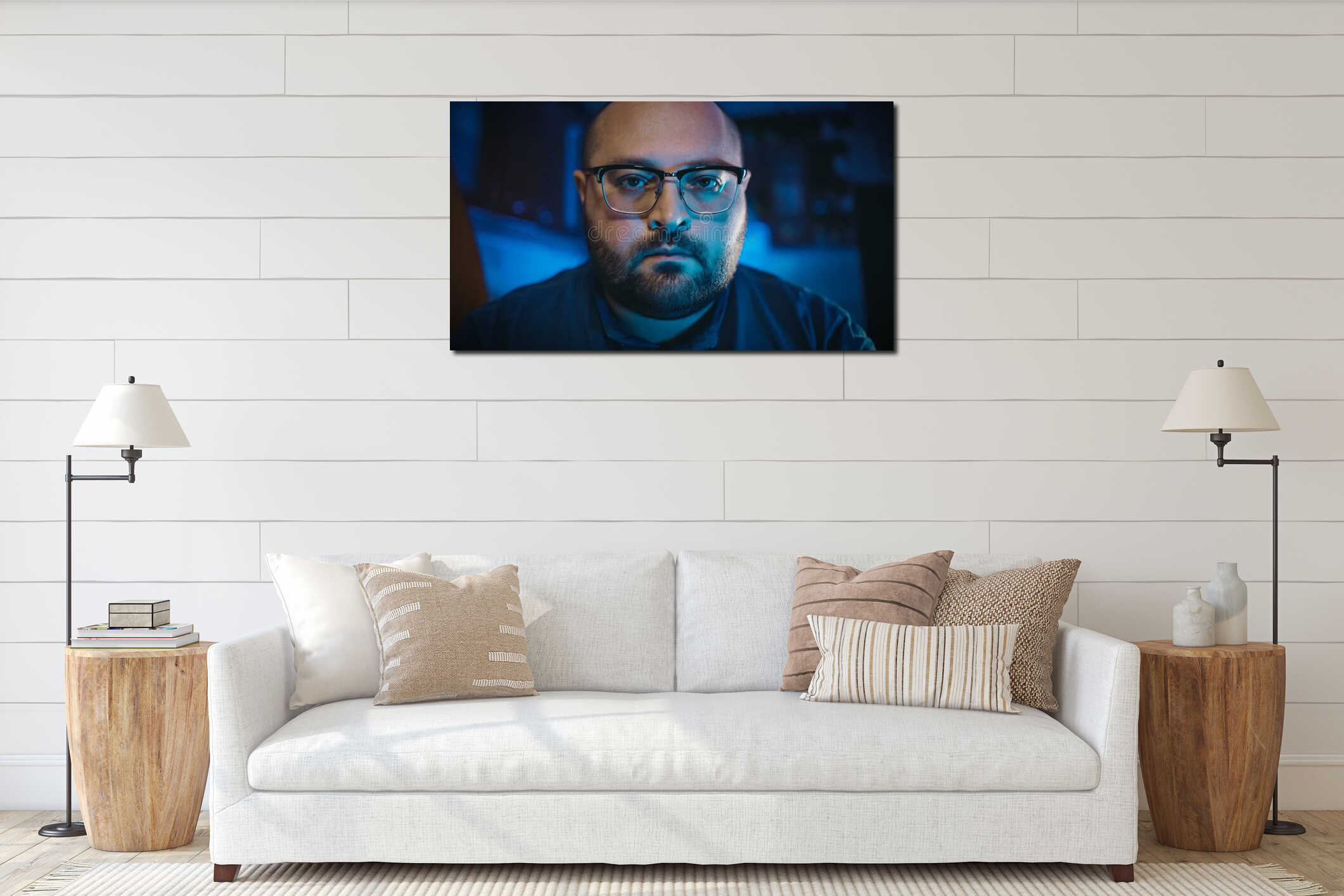 Portrait of serious bearded man in glasses looks at camera in evening or night dark room with blue color interior mockup