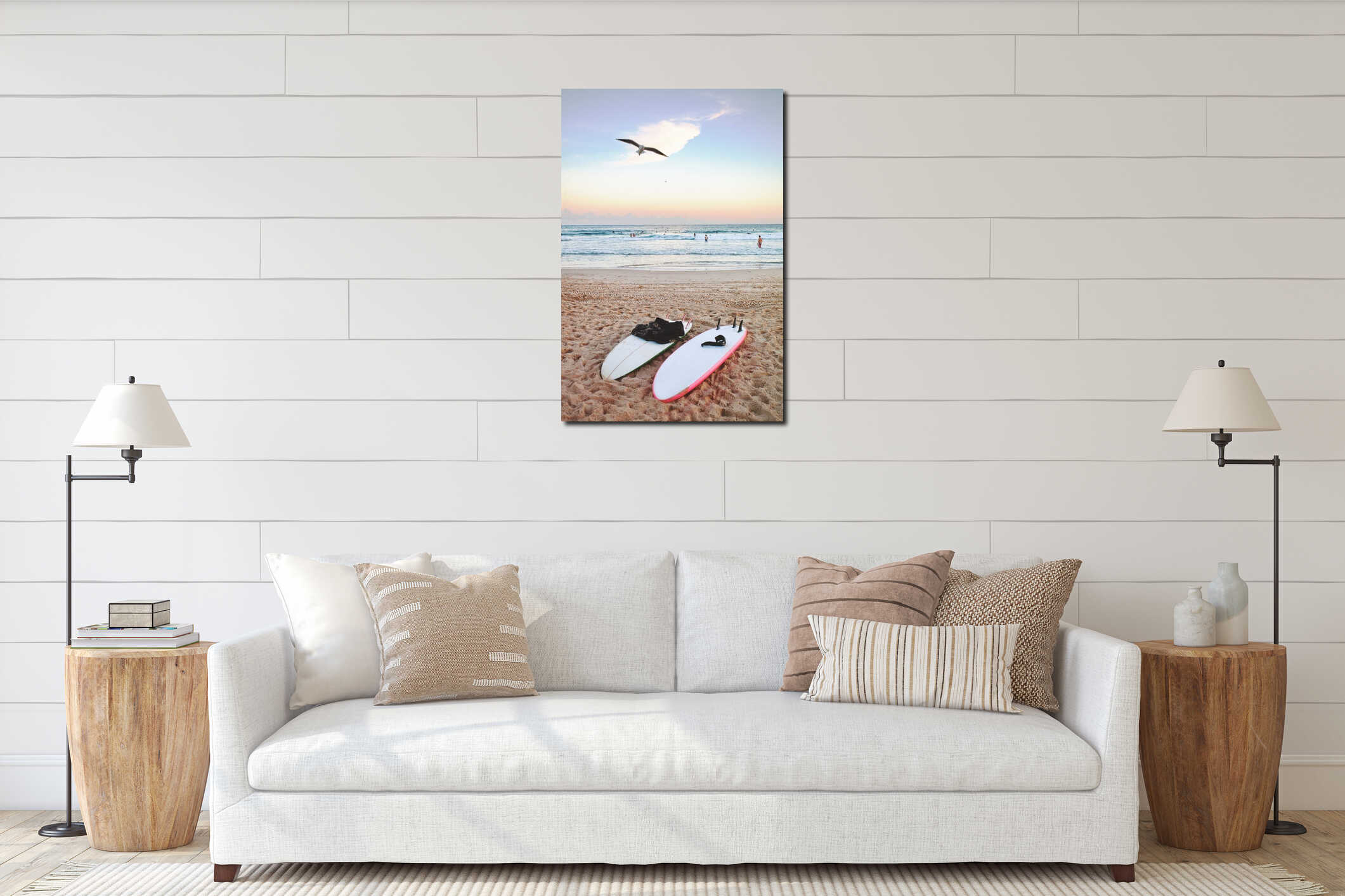 Vertical shot of surfboards on the sand near the sea with people in water and a seagull flying above interior mockup