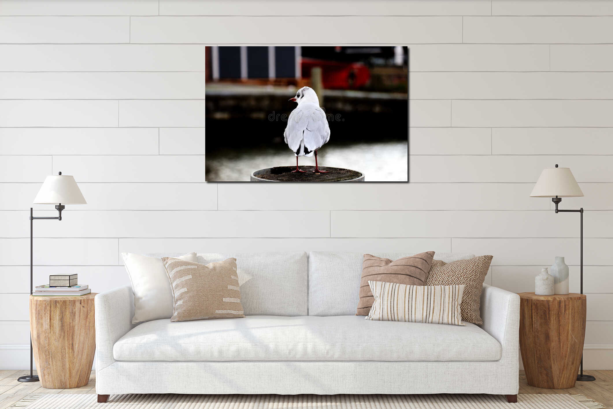 Rear view of young baby seagull standing on a wooden pole against river interior mockup