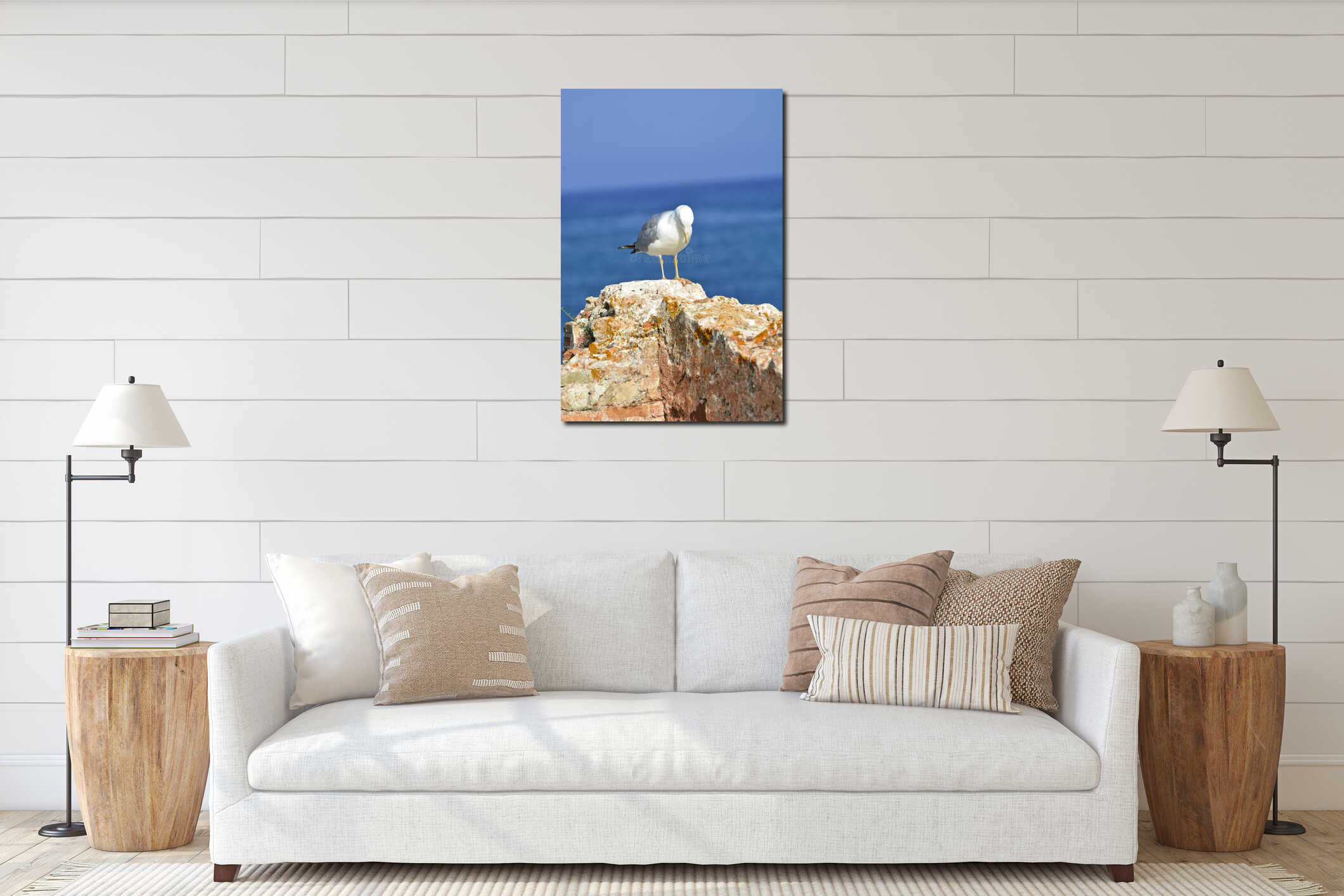 A seagull sitting on a stone wall, with the ocean and horizon in the background; with copyspace for designs interior mockup