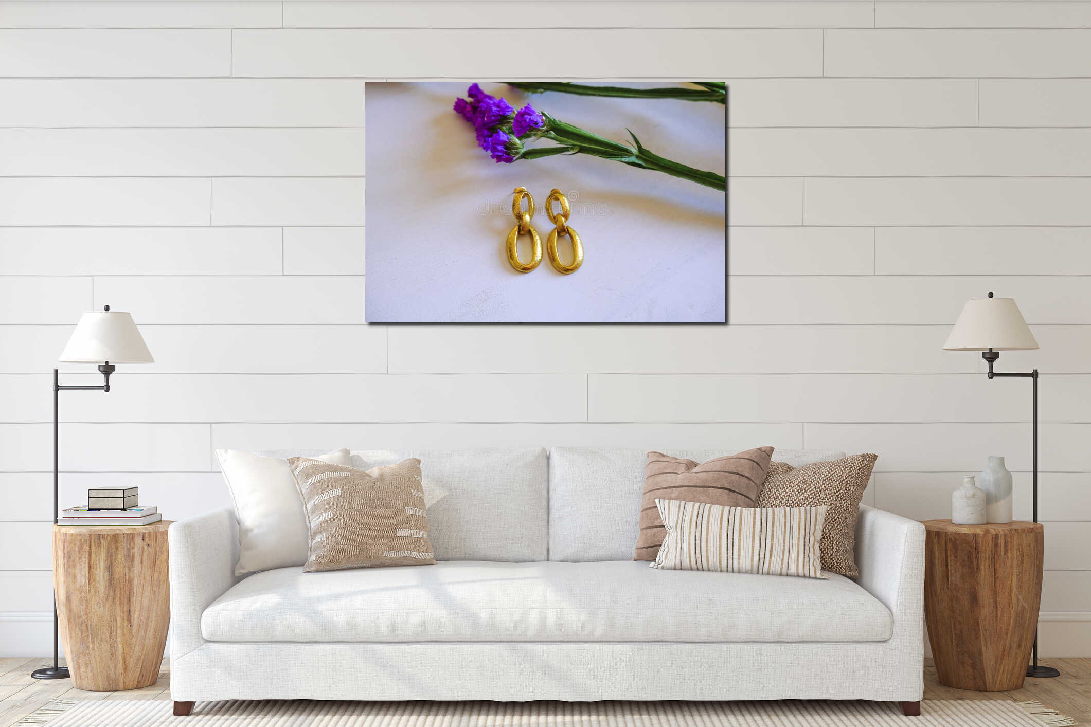 Golden elegant earrings on white wooden background across purple statice flowers. Top view. Copy space. Stylish flat lay interior mockup