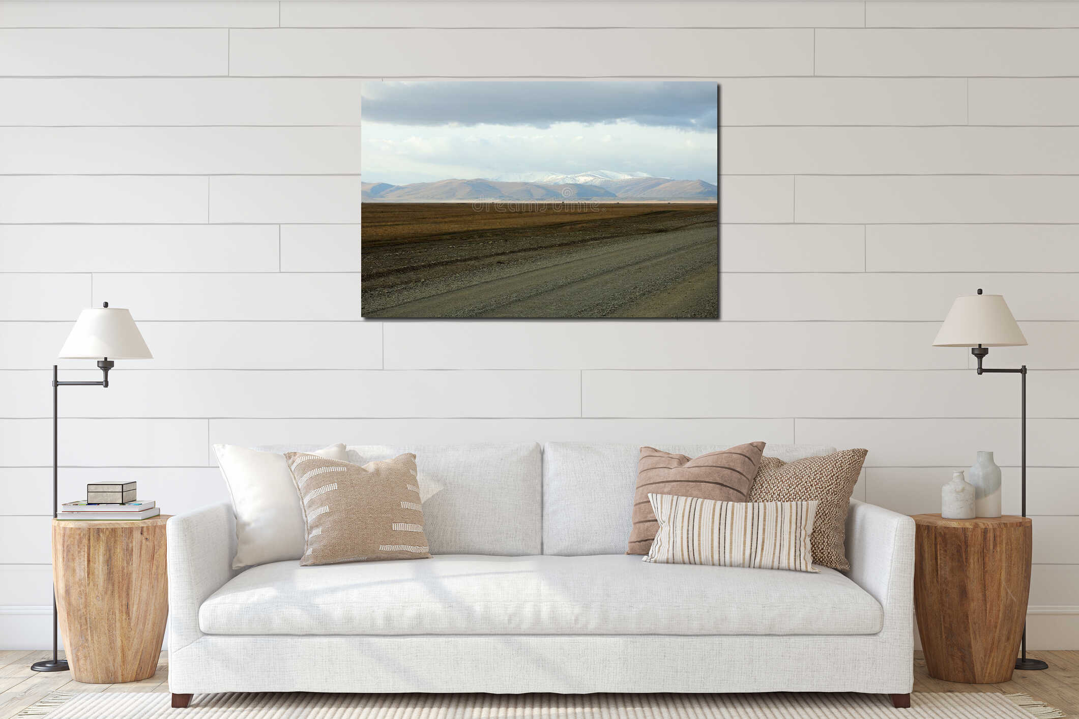 A field gravel road runs through an autumnal desert steppe at the foot of a mountain range interior mockup