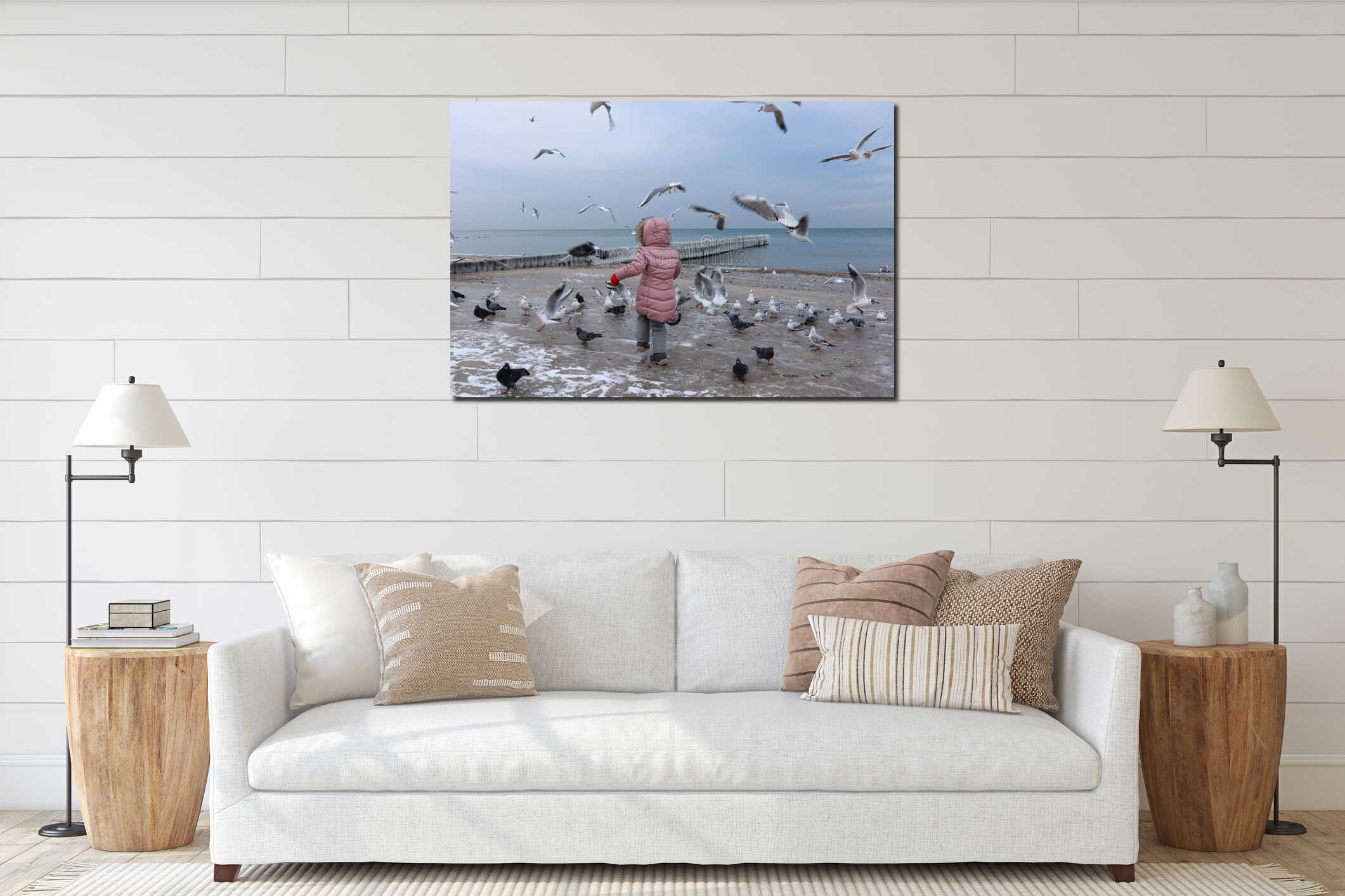 A little girl feeds seagulls on the Baltic Sea coast in winter. interior mockup