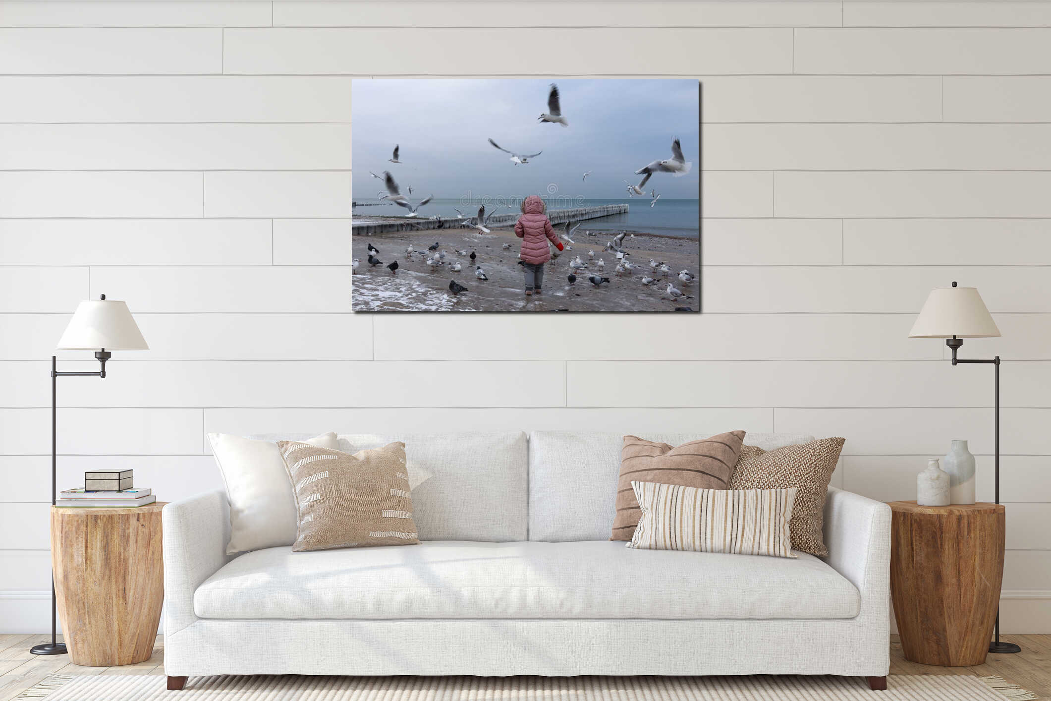 A little girl feeds seagulls on the Baltic Sea coast in winter. interior mockup