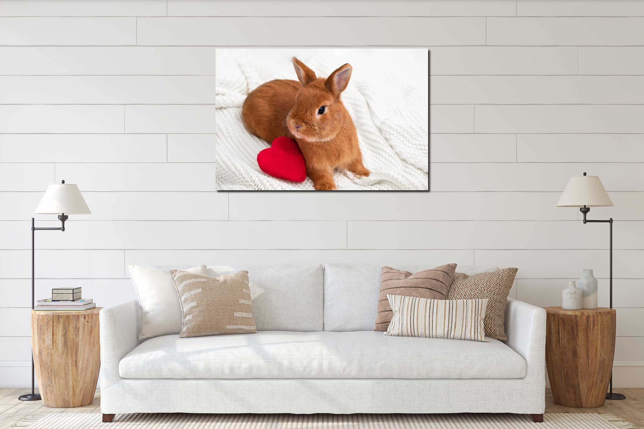Cute little ginger decorative bunny,rabbit looking at camera on white cozy plaid near red soft plush heart.Copy space interior mockup