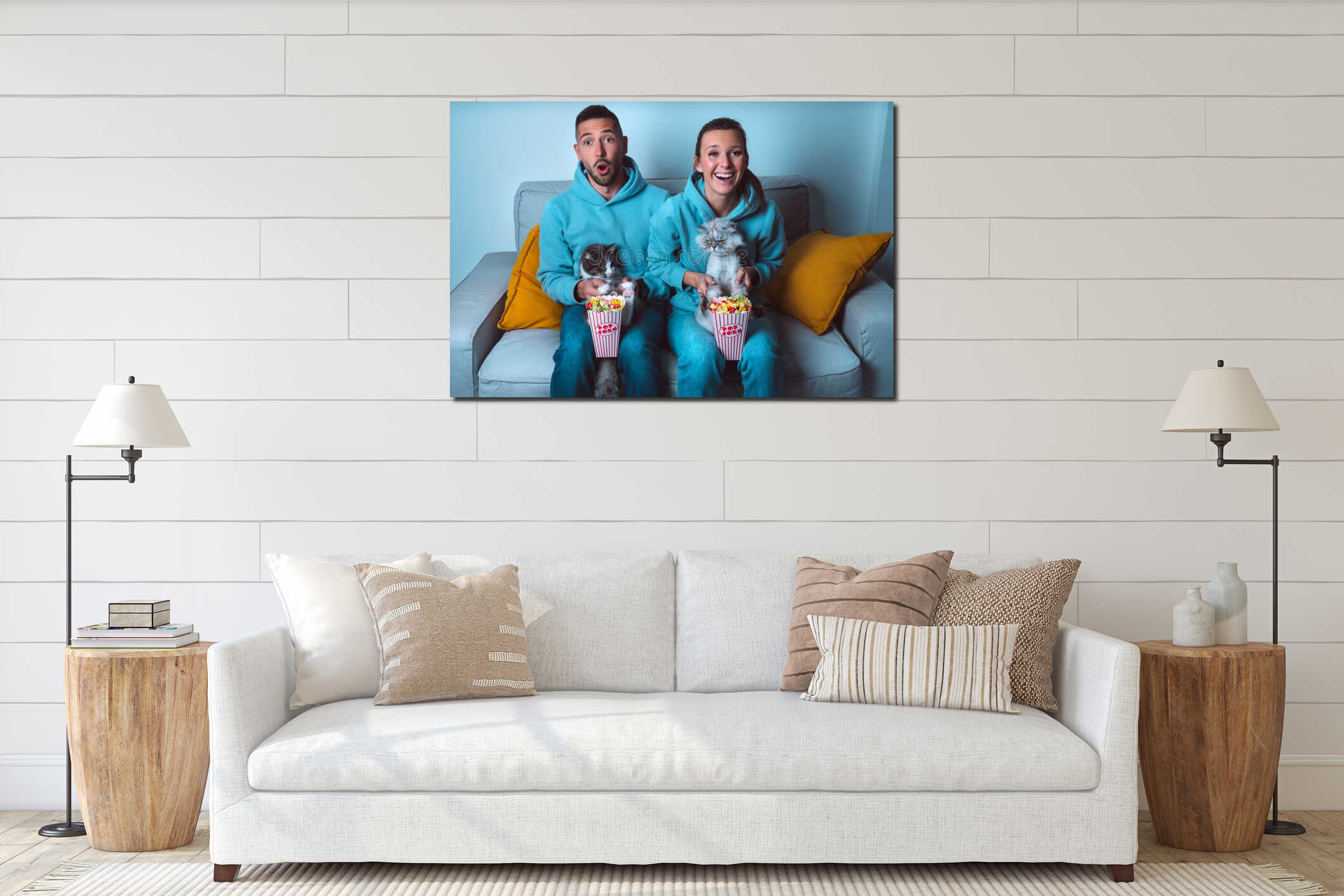 Young happy couple with popcorn and funny cats sitting on sofa watching comedy movie and enjoying time together at home interior mockup