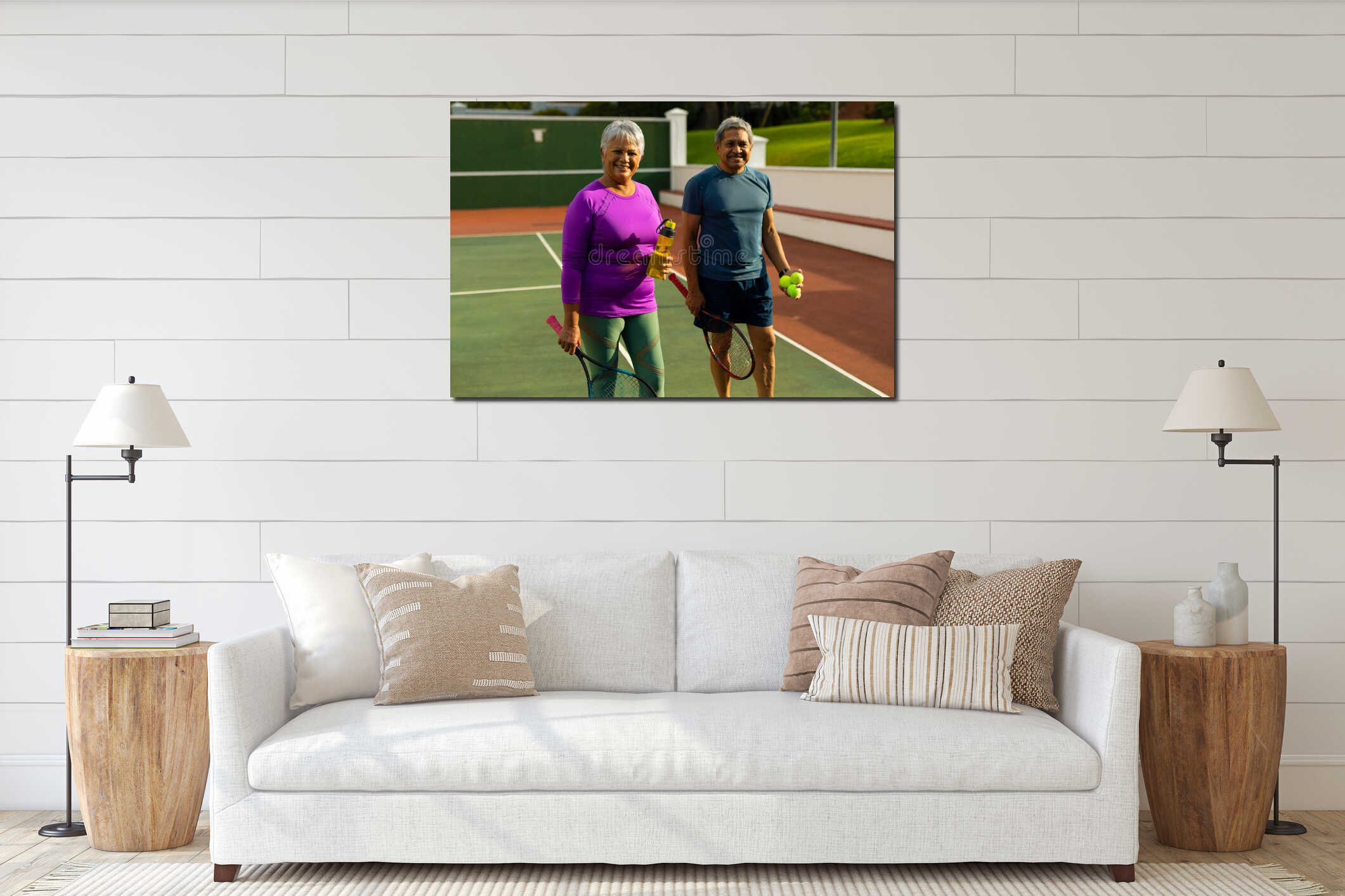 Portrait of smiling biracial senior couple holding rackets, balls and water bottle in tennis court interior mockup