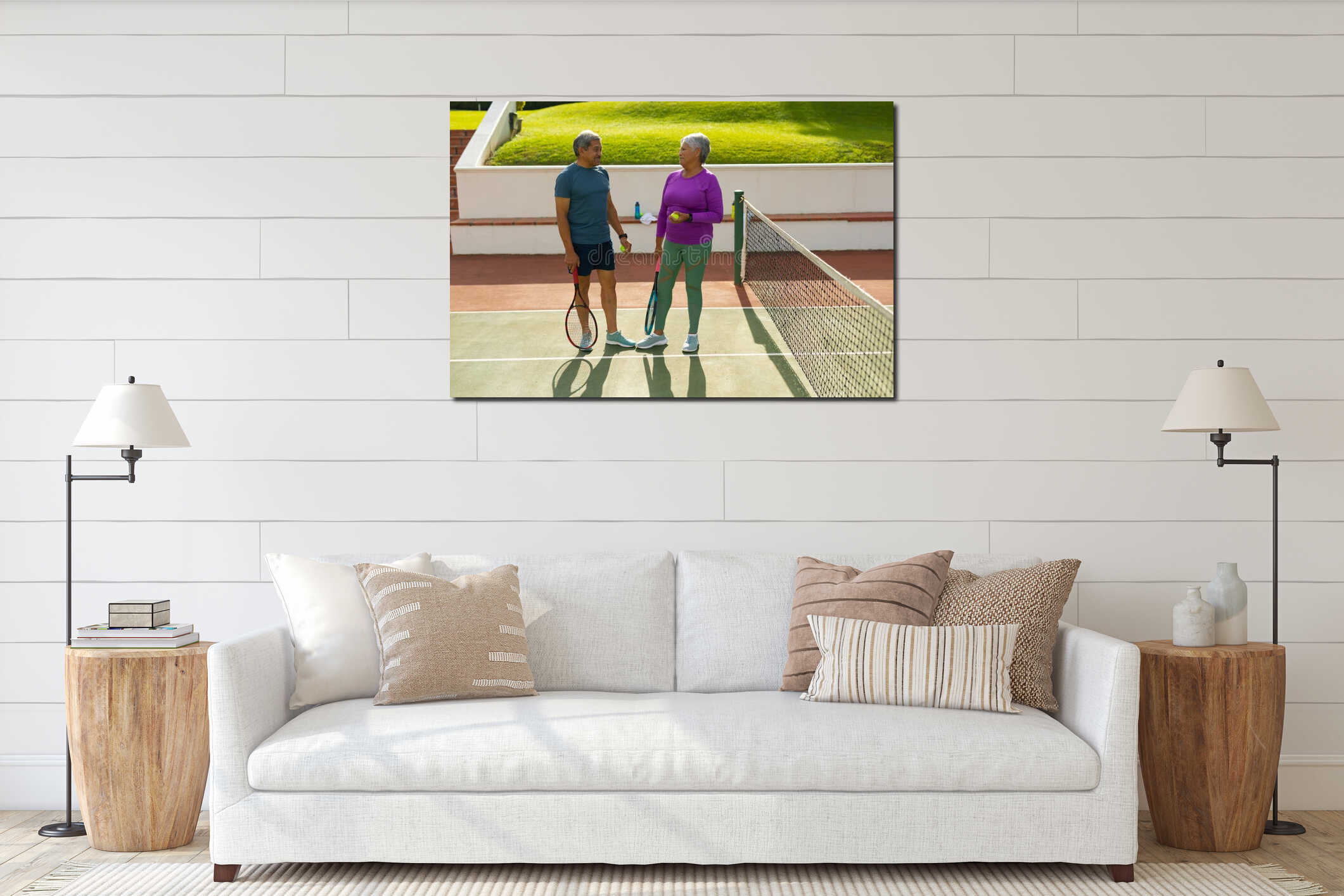 Biracial senior couple holding rackets and balls talking while standing by net at tennis court interior mockup