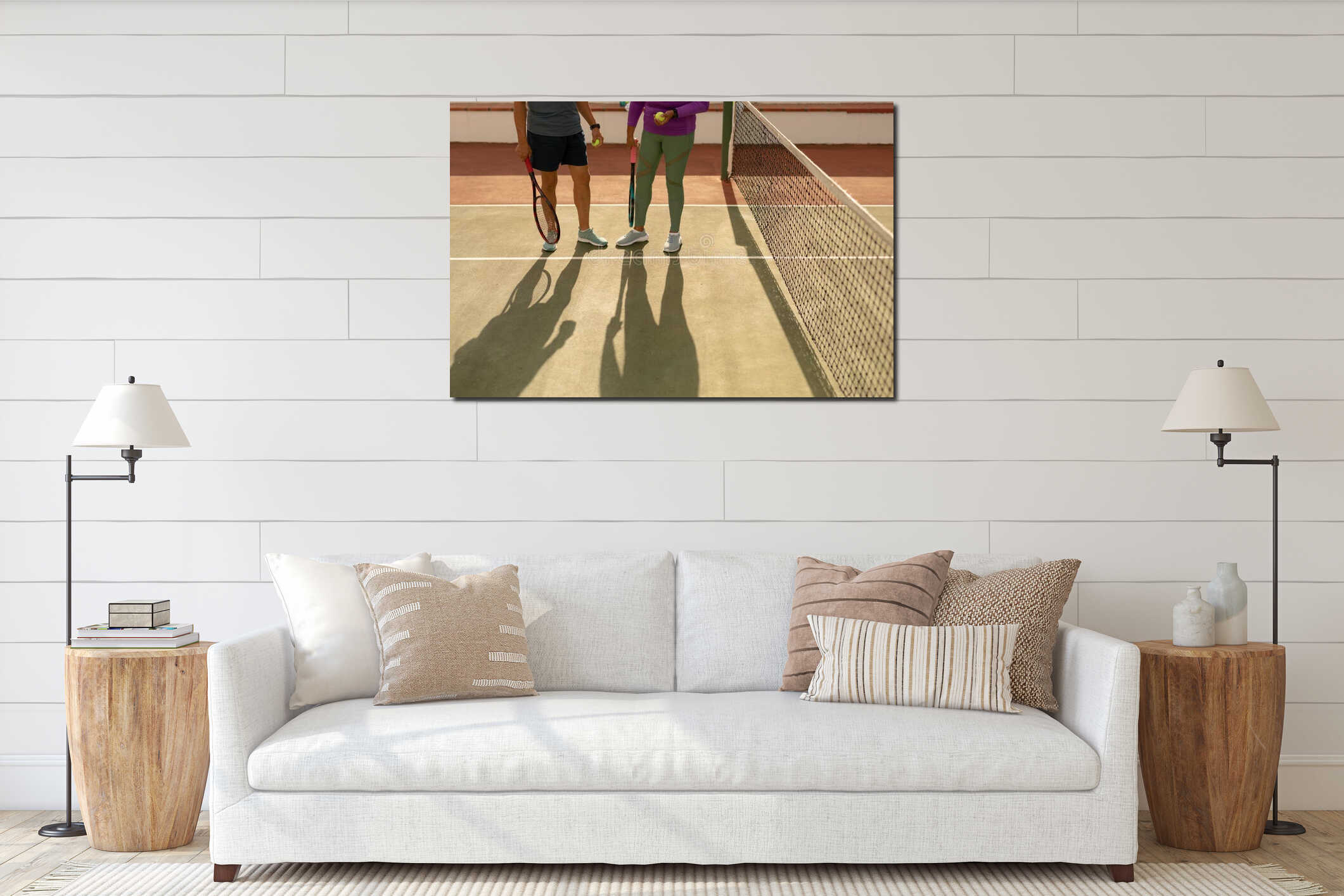Low section of biracial senior couple with rackets and balls standing by net at tennis court interior mockup