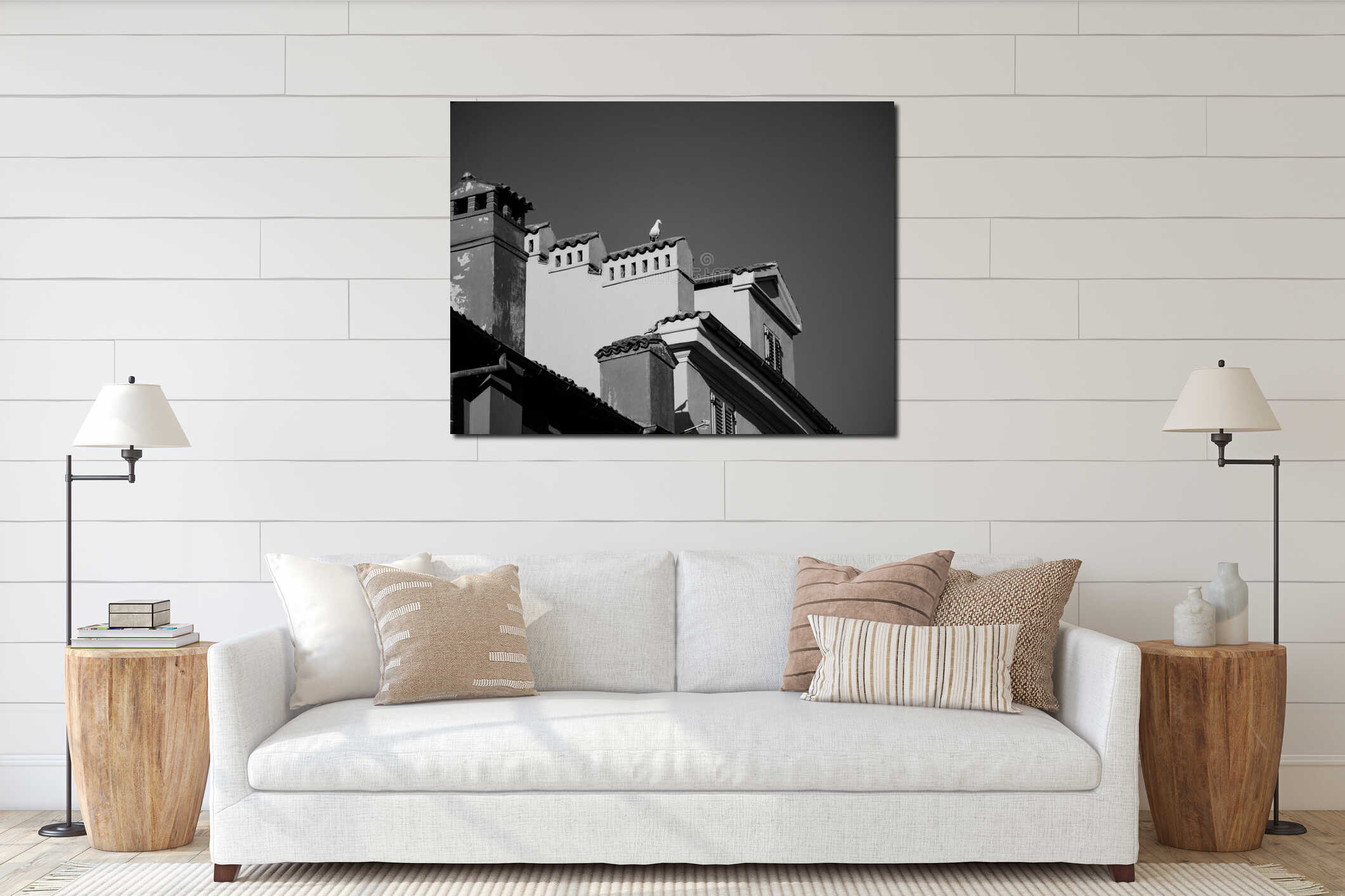 A seagull sits on the roof of an old house in the city center. Blue skies and colorful houses. Tiled roofs and ventilation pipes. interior mockup