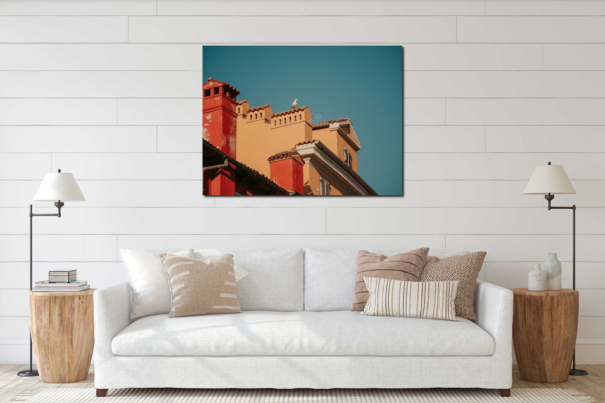 A seagull sits on the roof of an old house in the city center. Blue skies and colorful houses. Tiled roofs and ventilation pipes. interior mockup