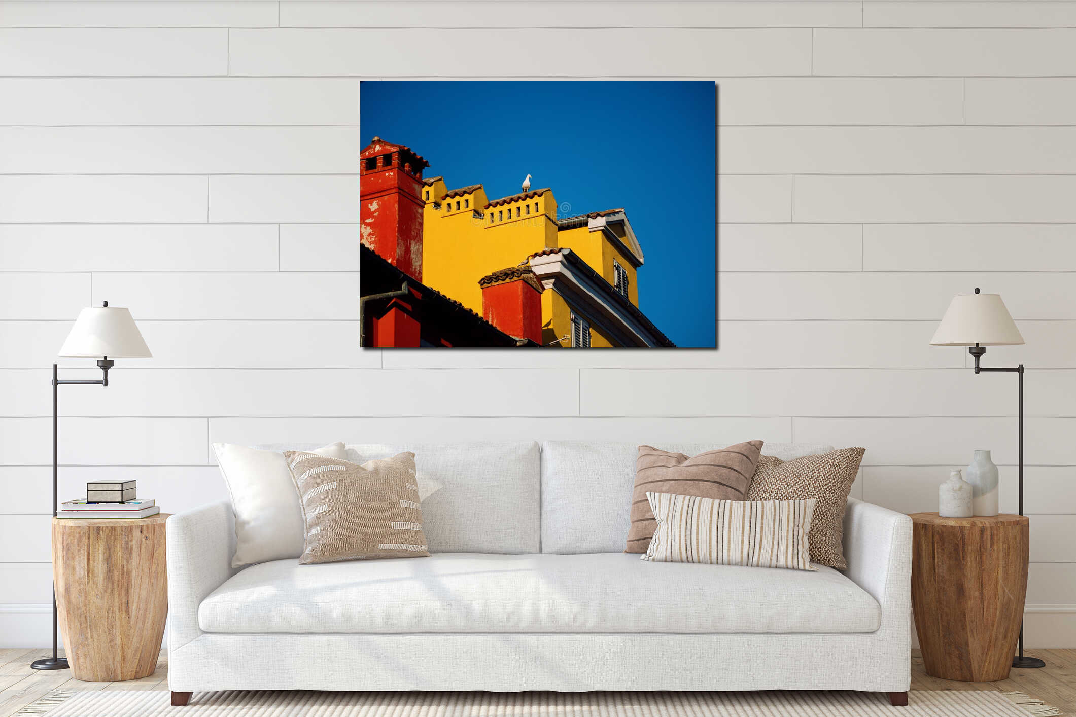 A seagull sits on the roof of an old house in the city center. Blue skies and colorful houses. Tiled roofs and ventilation pipes. interior mockup