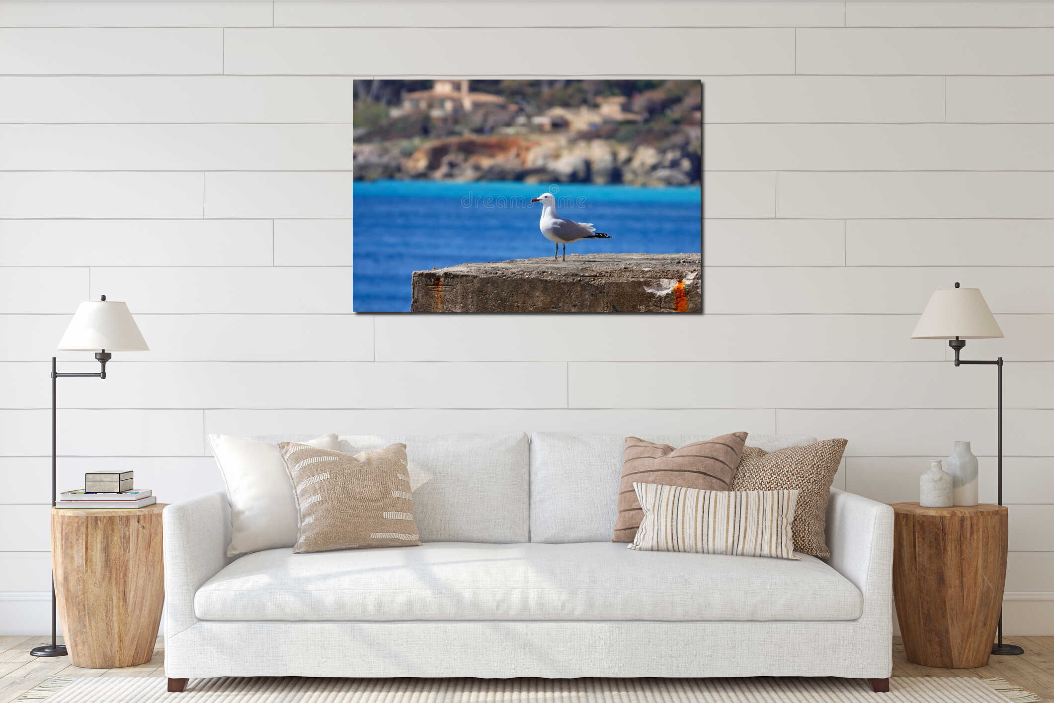 Seagull perched atop a concrete post near a tranquil sea in Cala Rajada, Mallorca interior mockup