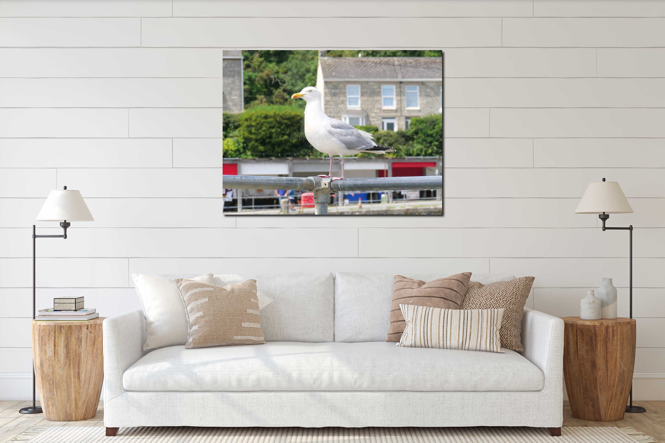 A seagull sits on a metal railing in front of a house at the harbor of Porthleven Cornwall England interior mockup