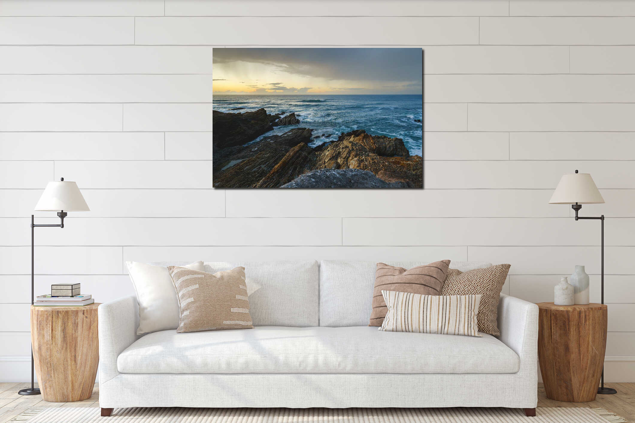 A serene rocky beach is bathed in the warm hues of a sunset, with dramatic clouds in the background interior mockup