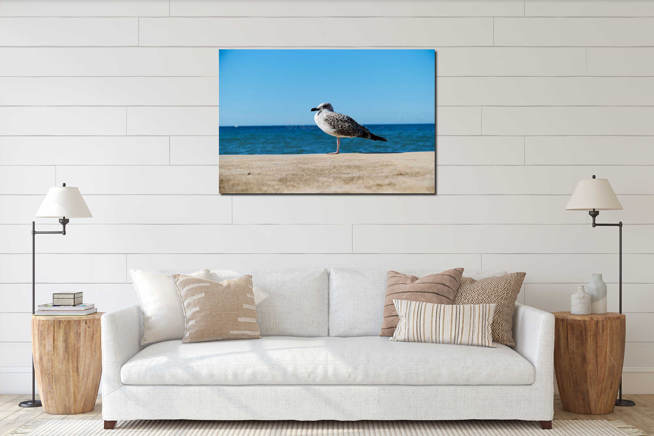 Juvenile seagull perched on the seaside against the backdrop of blue sea and sky interior mockup