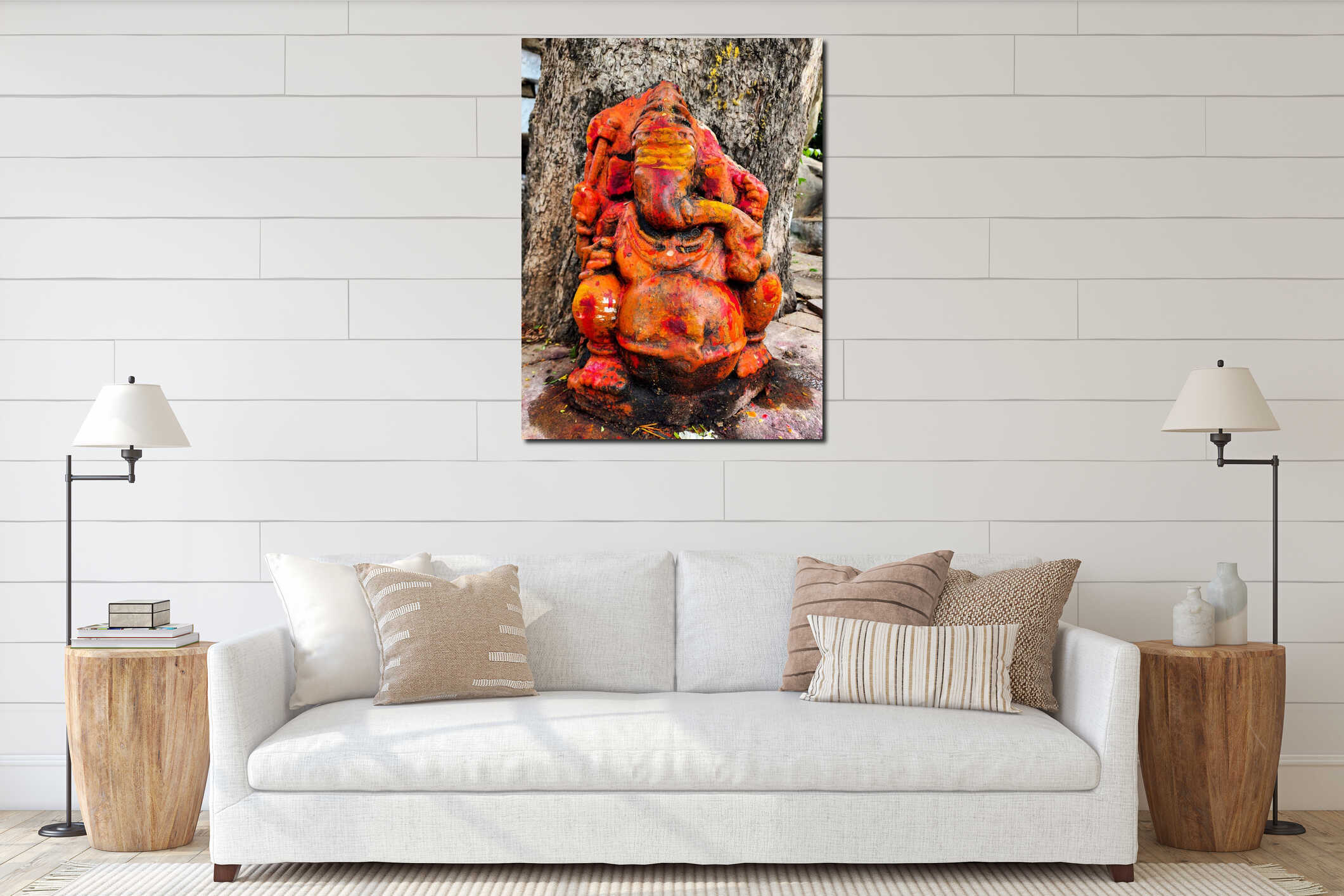 Stock photo of an old, rustic idol of lord Ganesha, painted with vibrant orange, is set against the backdrop of a large trees interior mockup