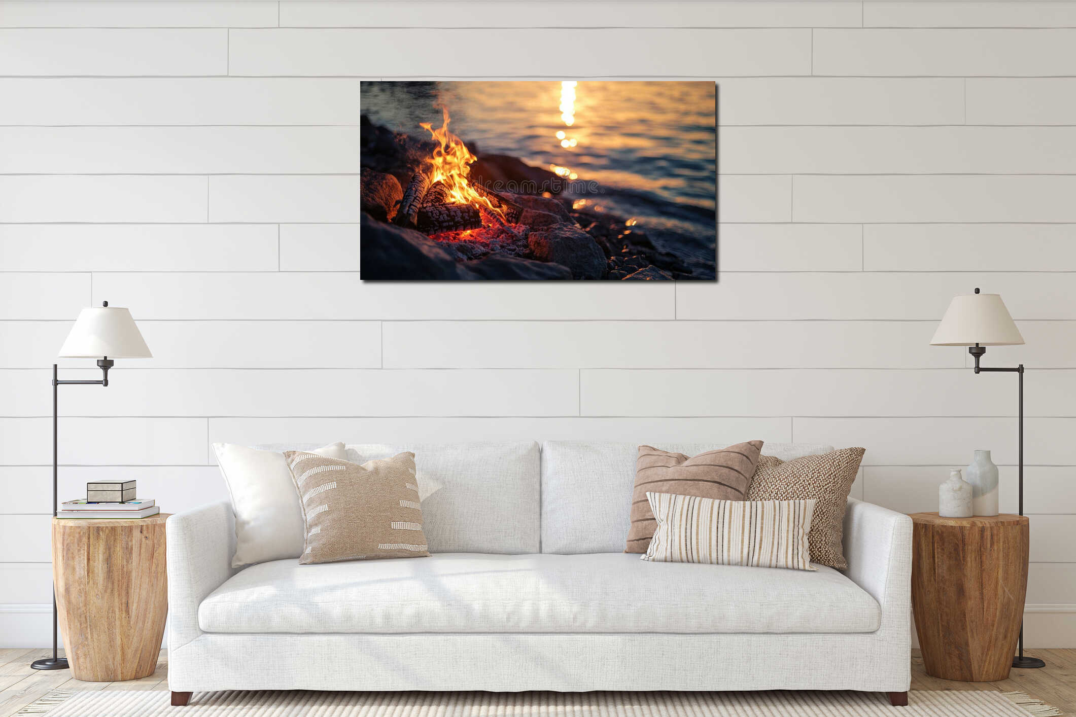 Campfire glowing on rocky beach with golden sunset reflected on water interior mockup