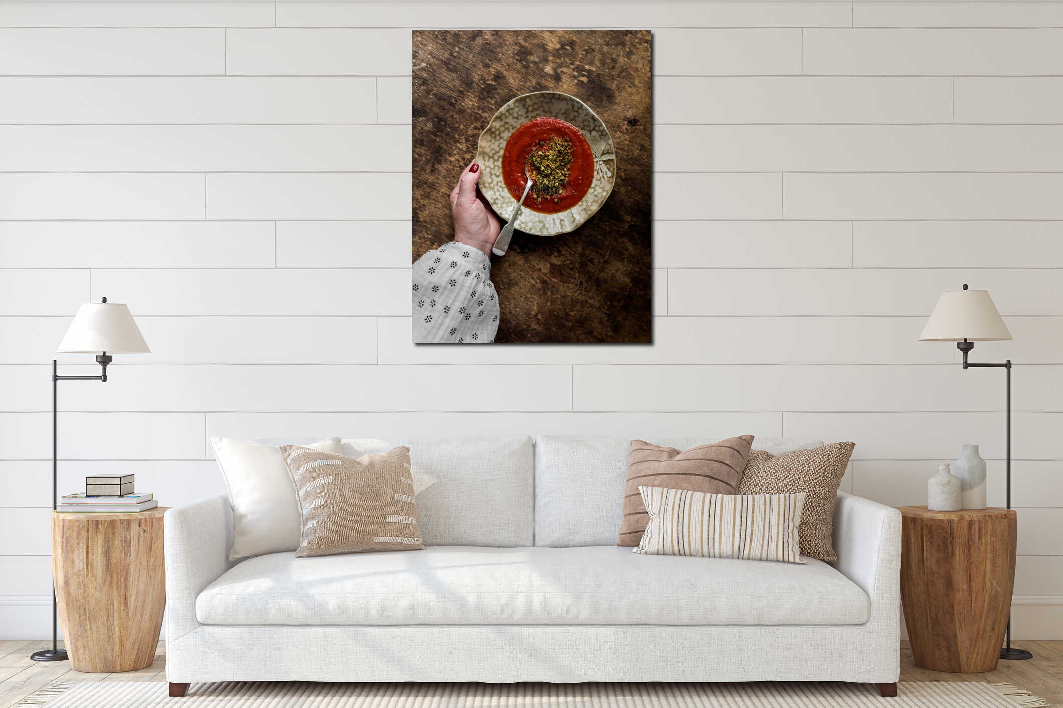 A woman's hand holds a plate with baked tomatoes cream soup with garlic herbs olive oil bread crumbs on a wooden table interior mockup