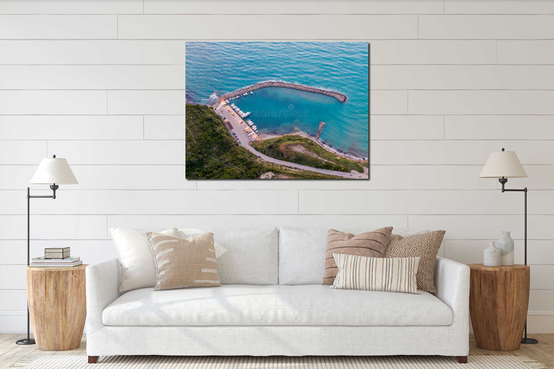 Coastal harbor with boats and clear water, seen from above. A scenic road winds along the hillside interior mockup