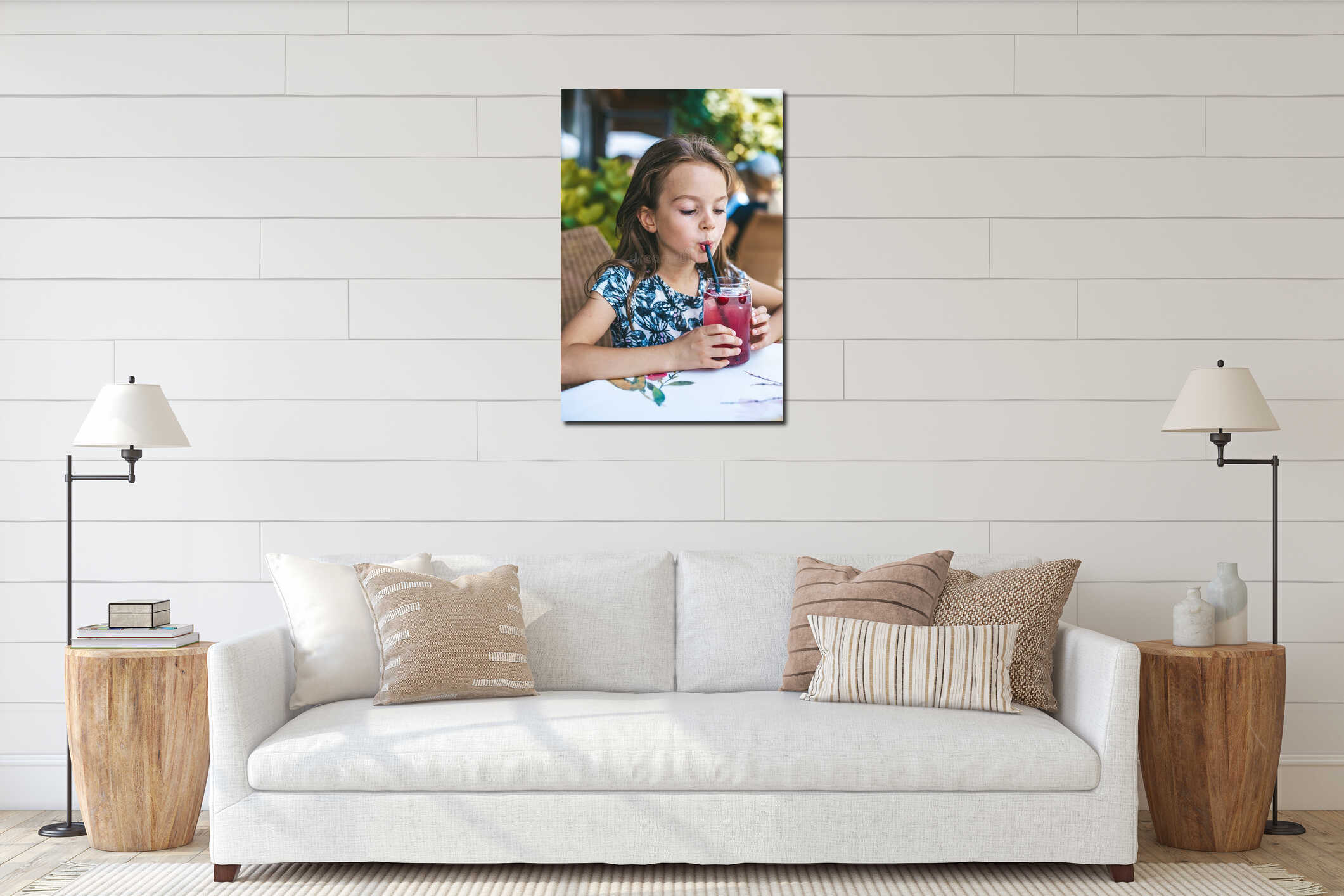 Little girl drinking a glass of pink-colored beverage with a straw and red cranberries floating in it, in an outdoor patio dining interior mockup