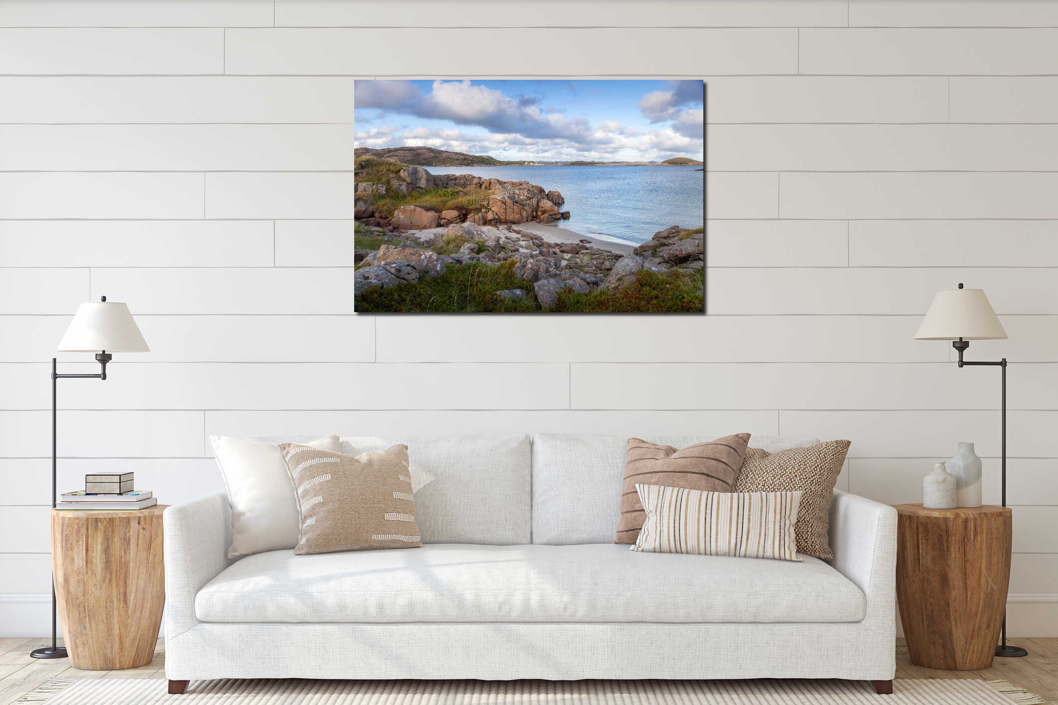 Serene coastal landscape with rocky shore, calm waters, and picturesque clouds under bright sky near remote island interior mockup