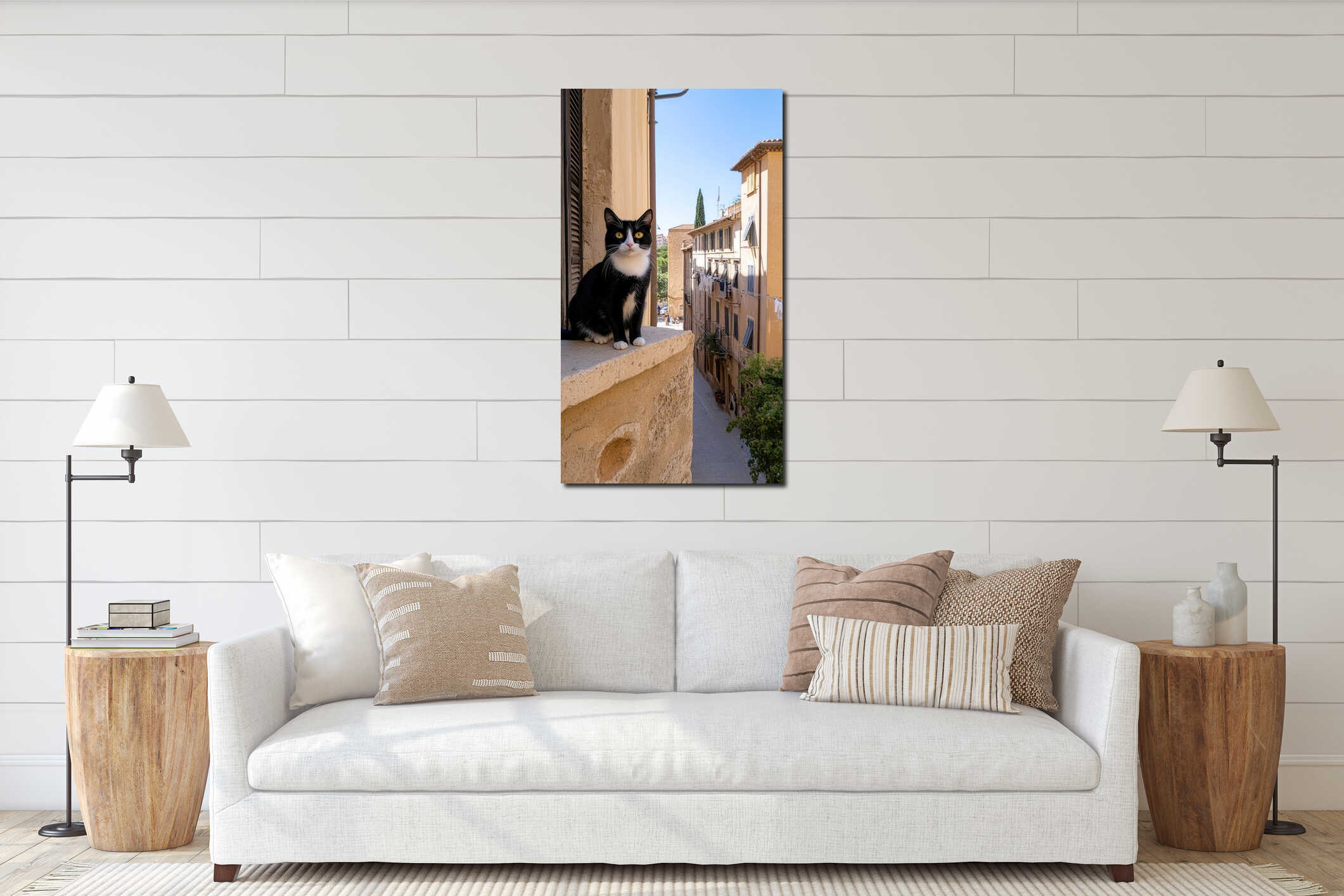 A black and white cat with bright yellow eyes lounges on an old stone wall as vibrant clothes flutter in the sunny urban landscape interior mockup