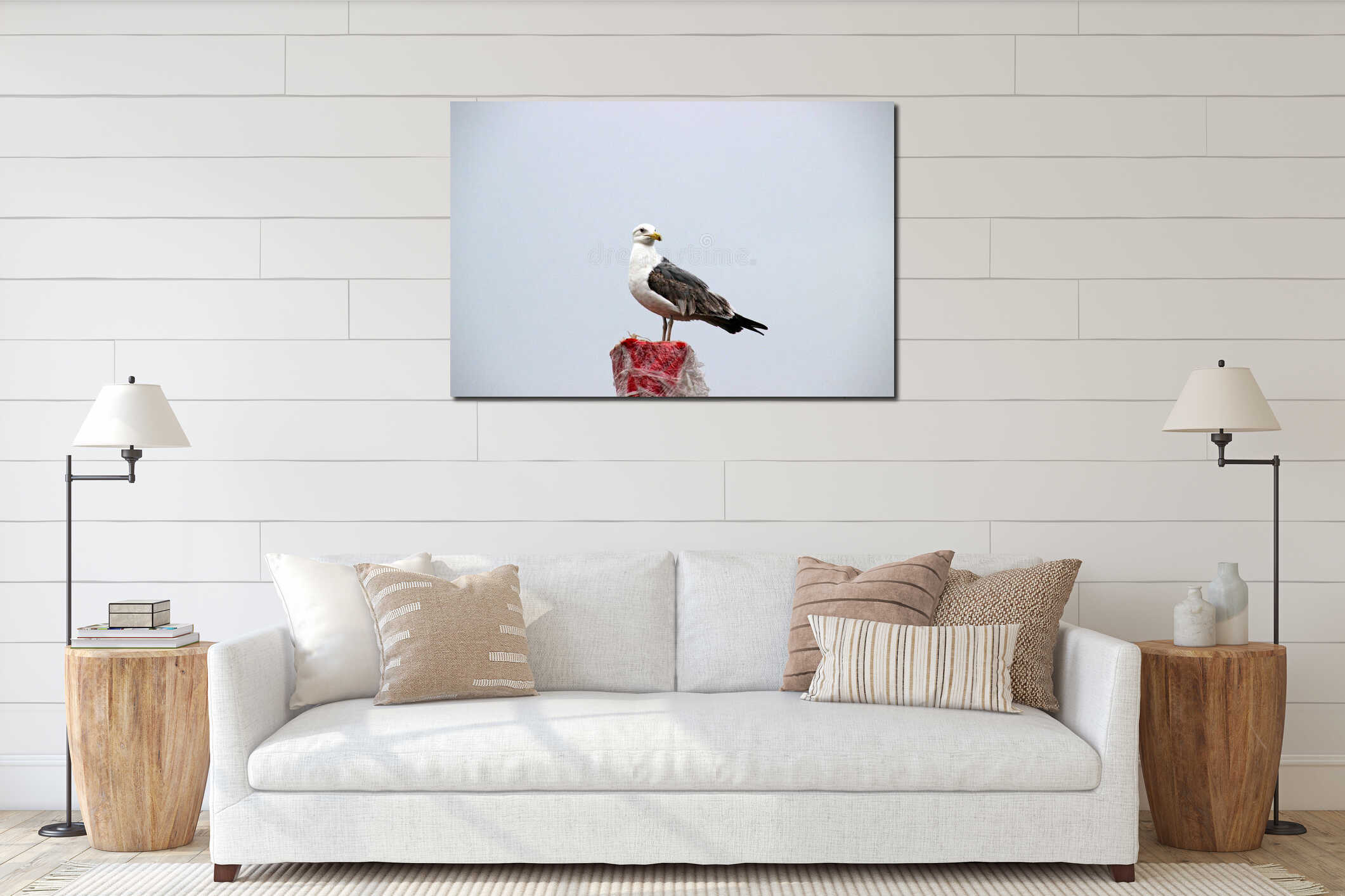Seagull perches atop a weathered post at a coastal location during an overcast day interior mockup