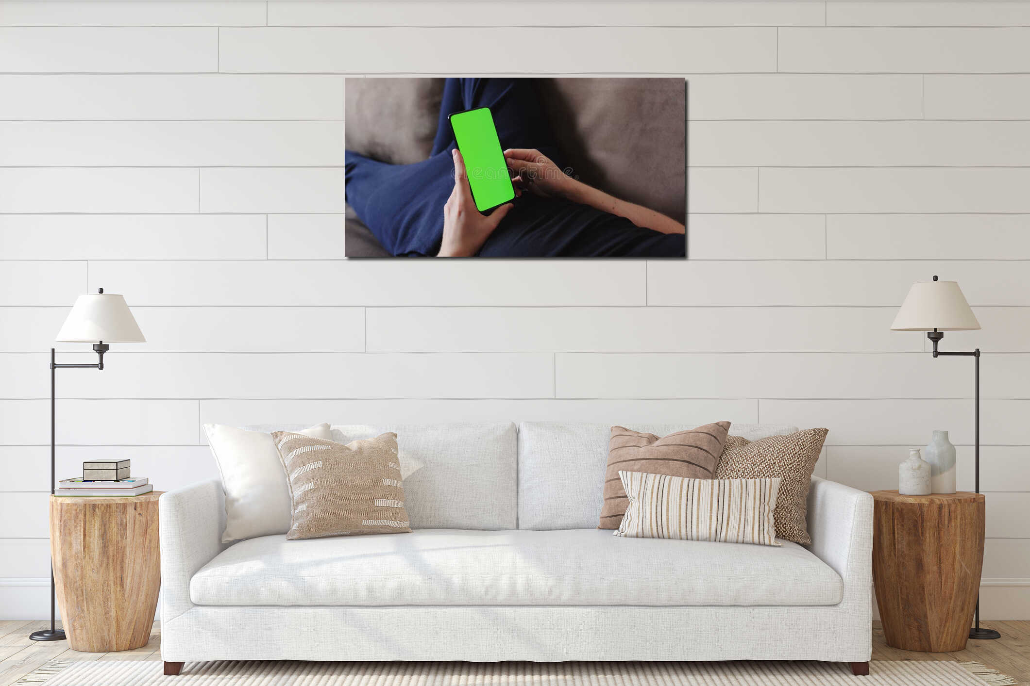 Closeup young man lying on a couch and holding smartphone with green screen interior mockup