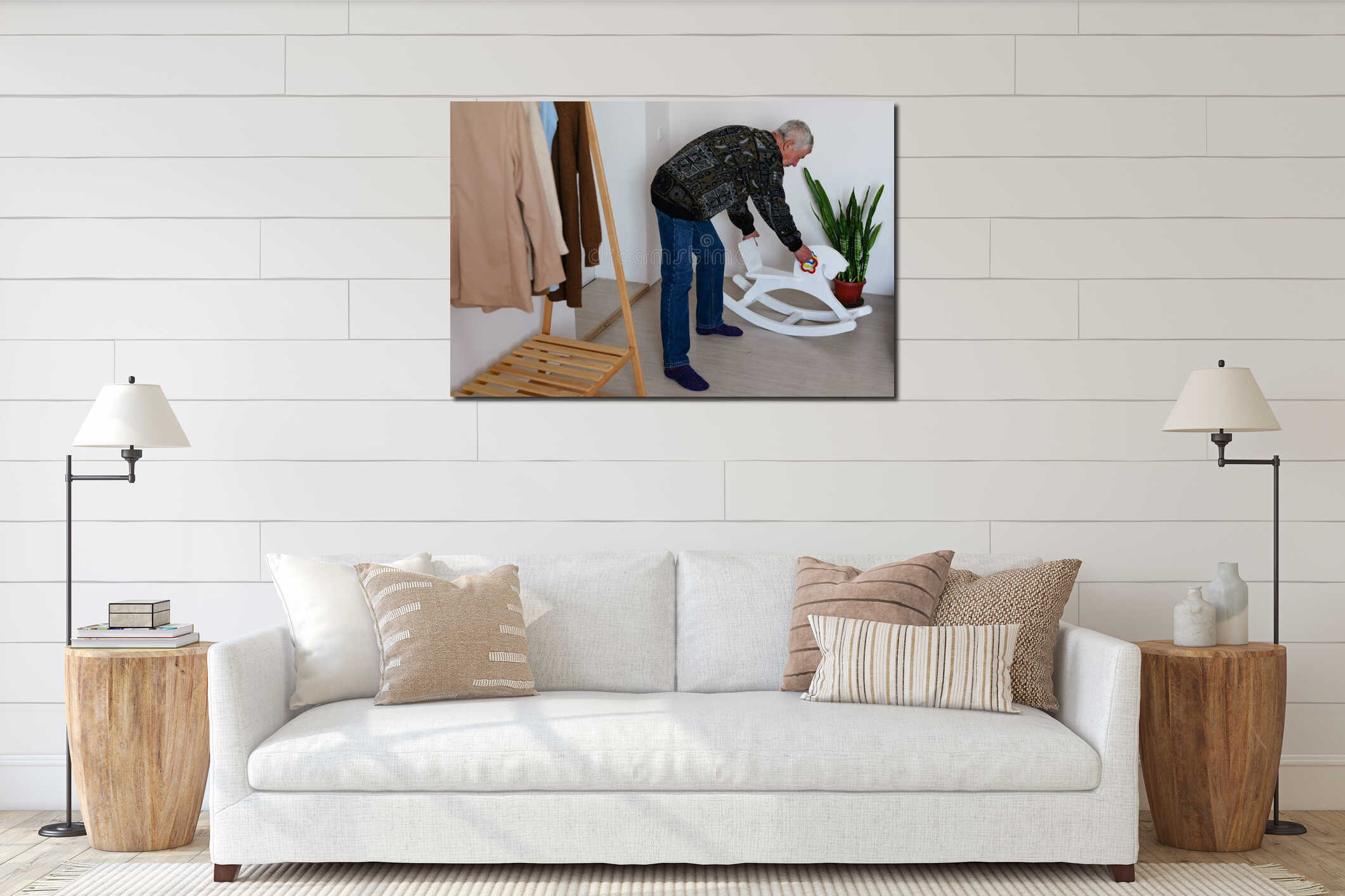 An elderly man adjusts a wooden rocking horse in a bright, welcoming room filled with greenery and clothing. Natural light interior mockup