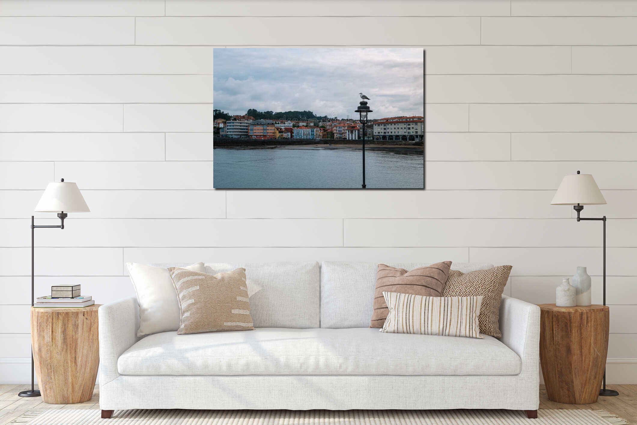 A seagull perches on a lamppost in front of a row of buildings in Luanco, a village in Asturias. interior mockup