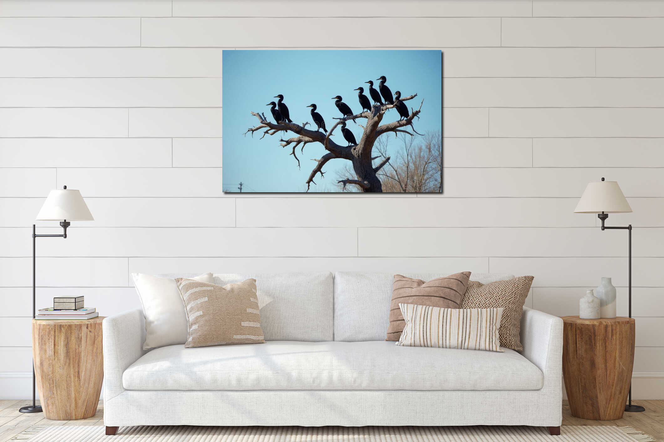 Group of black cormorants rest on dead tree branches under bright blue sky. Several birds perch together on weathered wood. Wild interior mockup