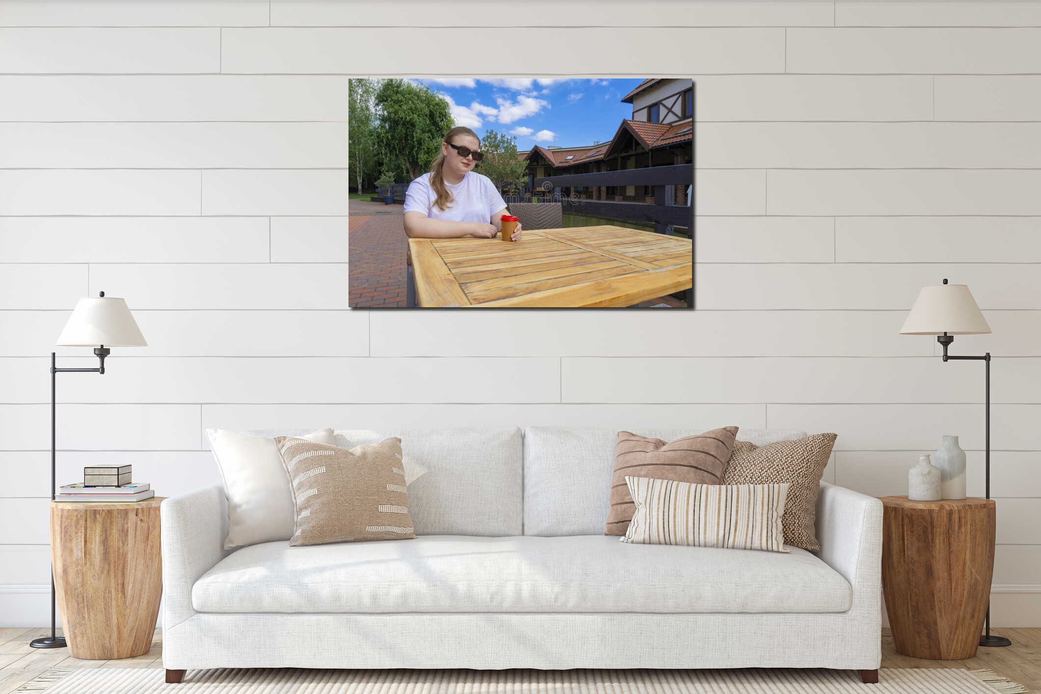 Young woman in sunglasses with coffee cup sitting at wooden table outdoors interior mockup