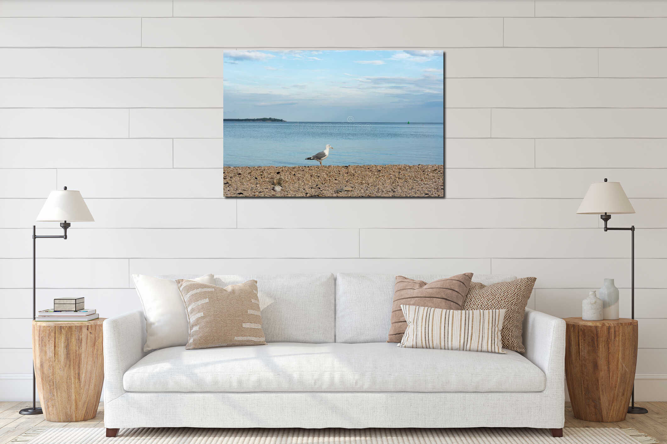 Lonely seagull standing on rocky pebble beach by calm blue sea on cloudy morning. interior mockup
