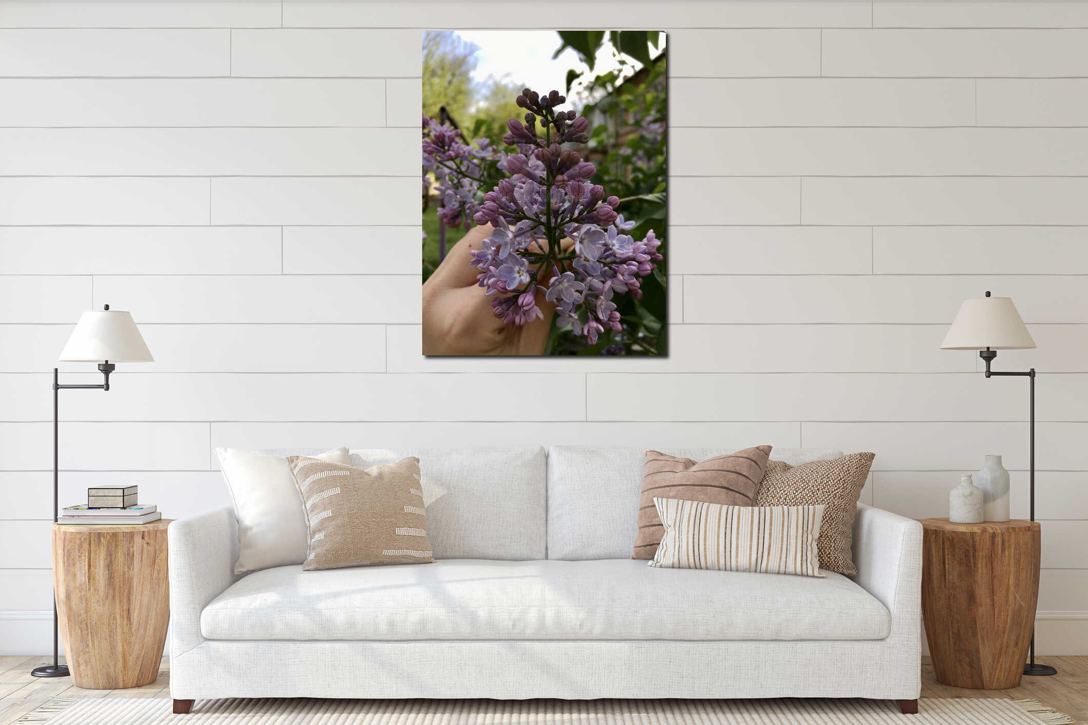 Light-purple lilac with four-petal flowers held by white female hand against blurred park alley, house, light sky vertical interior mockup