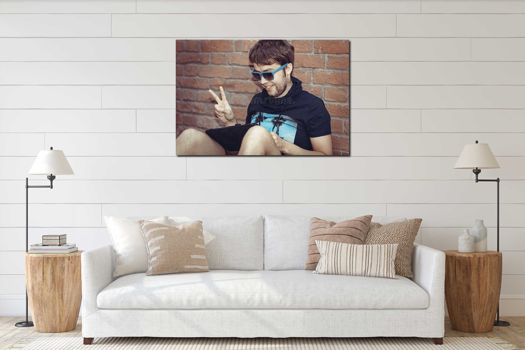 Young stylish hipster man using tablet sitting next to a brick w interior mockup