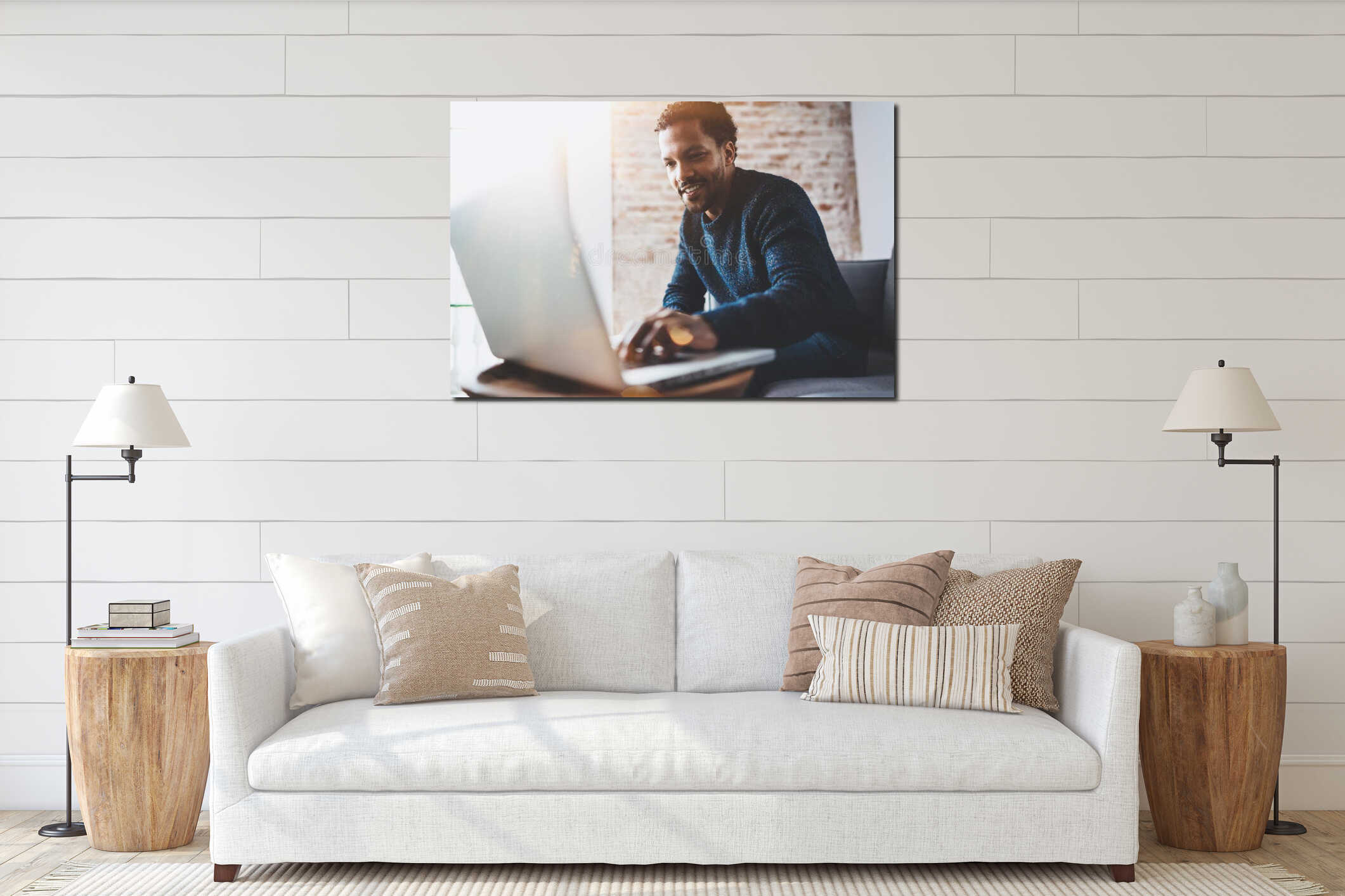 Cheerful African man using computer and smiling while sitting on the sofa.Concept of young business people working at interior mockup