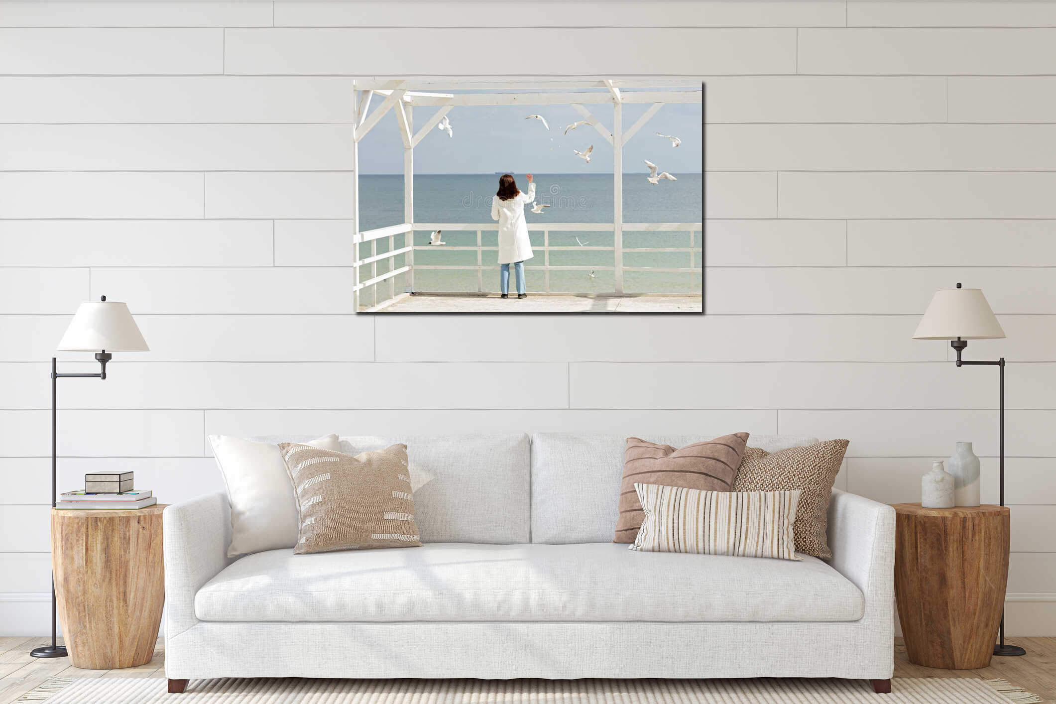 Young woman brunette in a white coat feeds the gulls on the be interior mockup