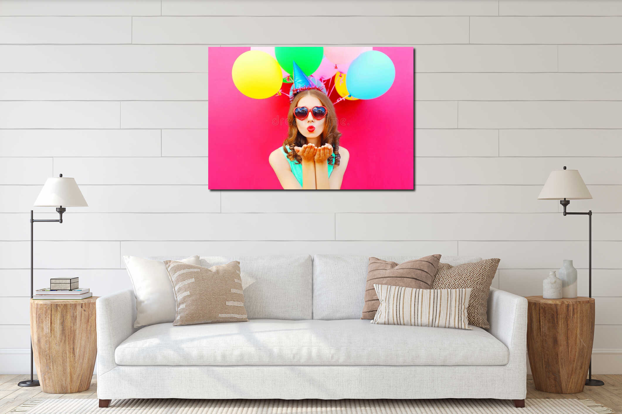 Portrait pretty woman in a birthday cap is sends an air kiss holds an air colorful balloons on pink background interior mockup